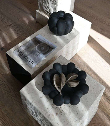 Künstlerische schwarze Keramikschalen auf minimalistischen Steintischen mit natürlichen Texturen