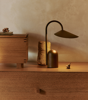 Elegante Tischleuchte mit skulpturalem Design auf einem Holzsideboard im sanften Umgebungslicht